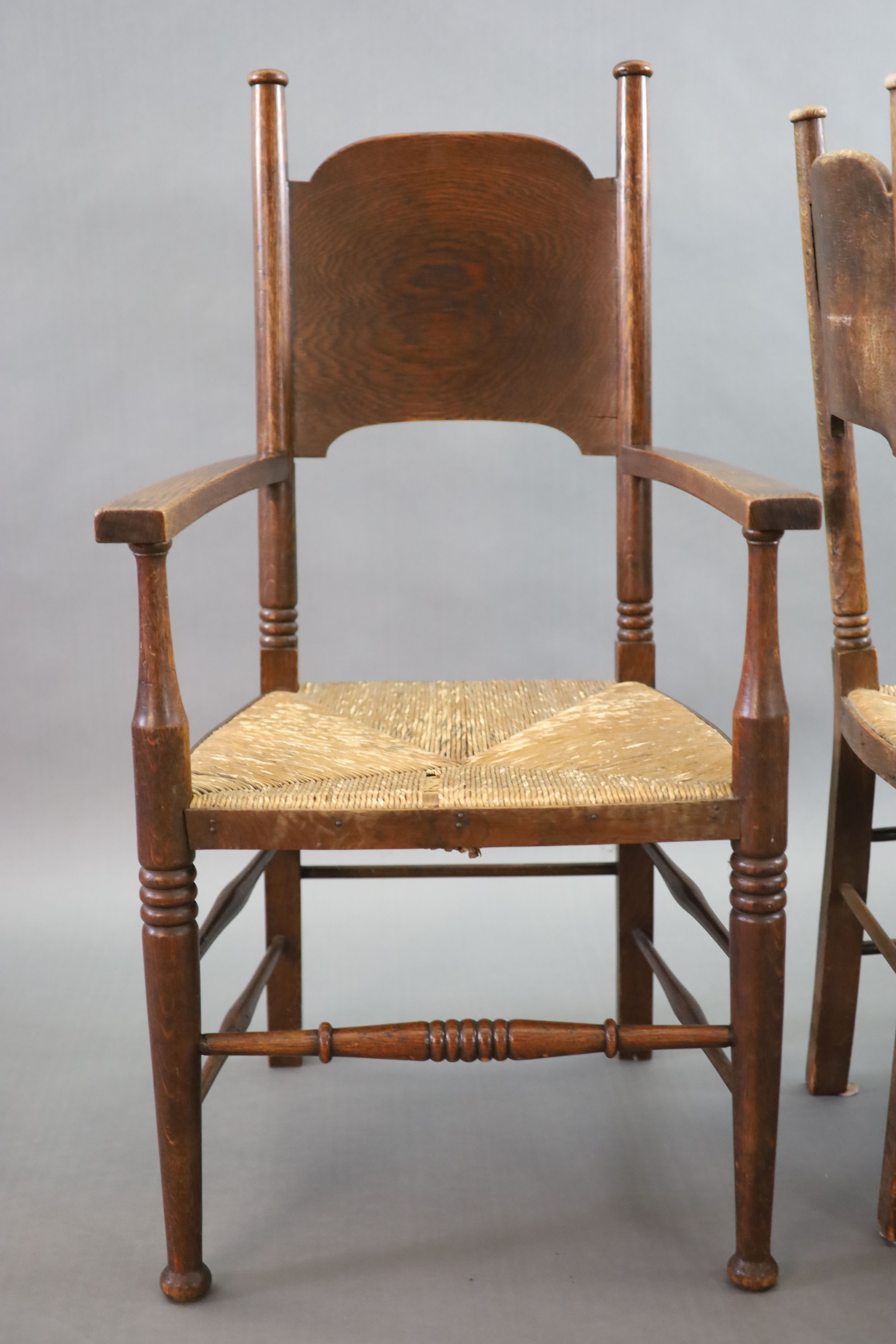 A set of six oak chairs, including a pair of carvers, in the Glasgow School manner by William Birch, High Wycombe, carvers W.58cm D.54cm H.109cm